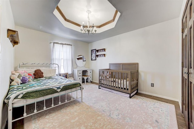 bedroom with a chandelier, a tray ceiling, crown molding, and baseboards