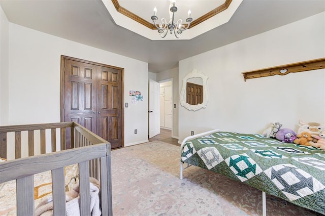 bedroom with a closet, a raised ceiling, a notable chandelier, and baseboards