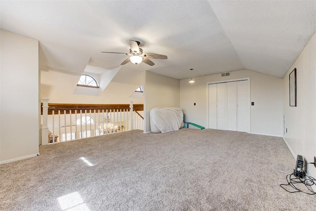 additional living space featuring visible vents, lofted ceiling, ceiling fan, a textured ceiling, and carpet floors