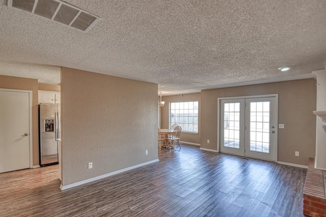 interior space with visible vents, a textured wall, baseboards, and wood finished floors