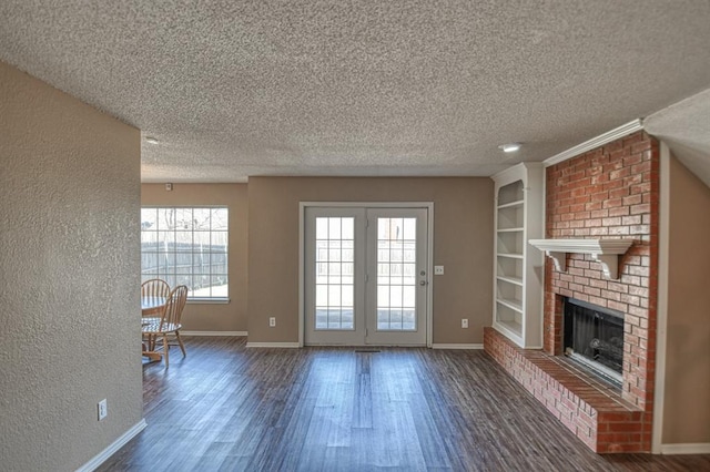 unfurnished living room featuring dark wood-style floors, a brick fireplace, a textured ceiling, and baseboards