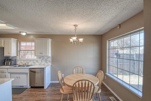 dining space with a chandelier, a wealth of natural light, dark wood-style flooring, and baseboards