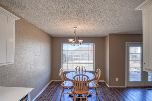 dining area with a textured wall, a notable chandelier, dark wood finished floors, and baseboards