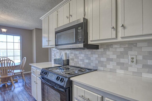 kitchen featuring decorative backsplash, stainless steel microwave, light countertops, and black electric range oven