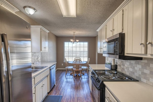 kitchen featuring dark wood-style flooring, decorative light fixtures, light countertops, appliances with stainless steel finishes, and white cabinetry