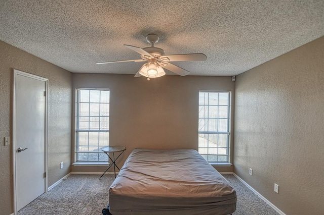 bedroom featuring a textured wall, multiple windows, and light colored carpet