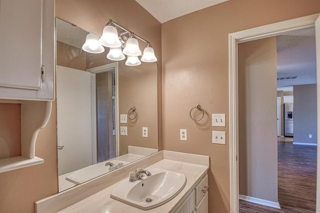 bathroom with visible vents, an inviting chandelier, vanity, wood finished floors, and baseboards