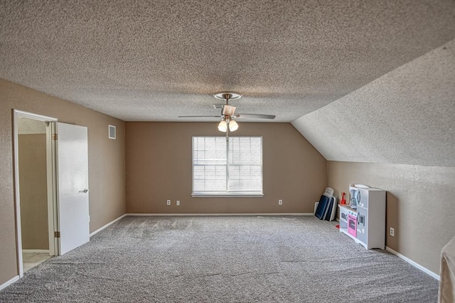 additional living space featuring visible vents, carpet flooring, vaulted ceiling, a textured ceiling, and baseboards