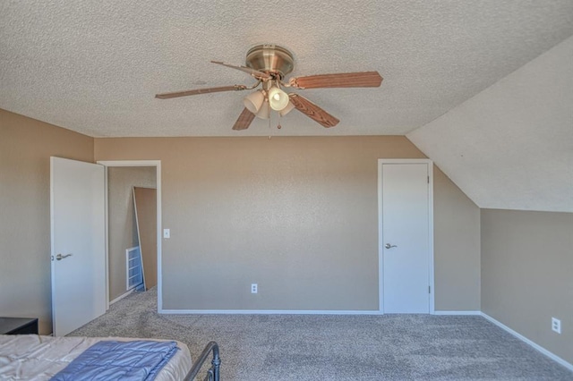 unfurnished bedroom featuring a textured ceiling, ceiling fan, lofted ceiling, carpet floors, and baseboards