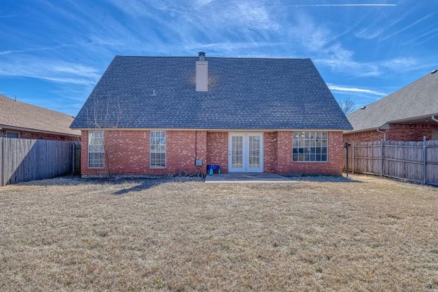 rear view of house with a patio, a fenced backyard, brick siding, a shingled roof, and a chimney