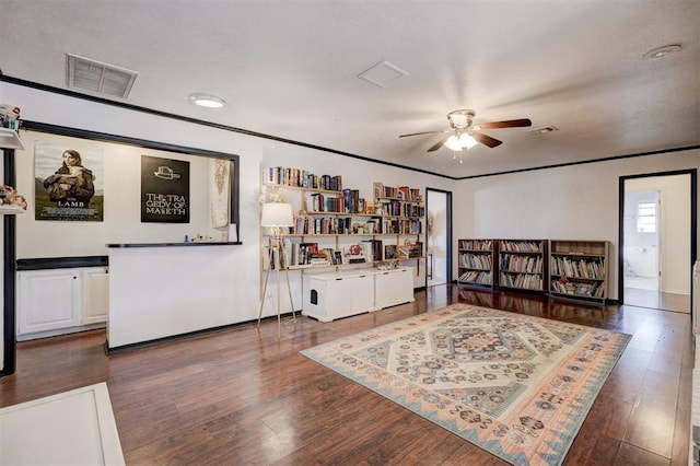 living area featuring a ceiling fan, crown molding, visible vents, and wood finished floors