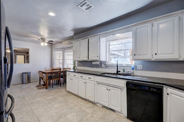 kitchen with black appliances, dark countertops, visible vents, and white cabinetry