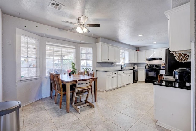 kitchen featuring dark countertops, white cabinets, a healthy amount of sunlight, and black appliances