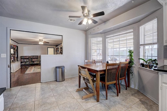 dining area with light tile patterned floors, a textured ceiling, visible vents, baseboards, and a ceiling fan