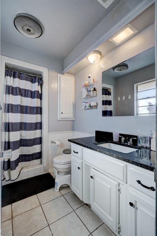 bathroom with tile patterned flooring, a shower with shower curtain, vanity, and toilet