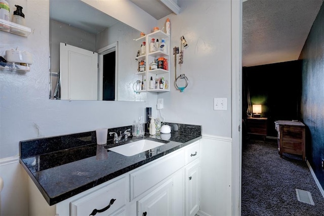 bar featuring wainscoting, dark colored carpet, a textured ceiling, bar area, and a sink