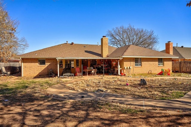 rear view of property with a patio area, brick siding, fence, and a chimney