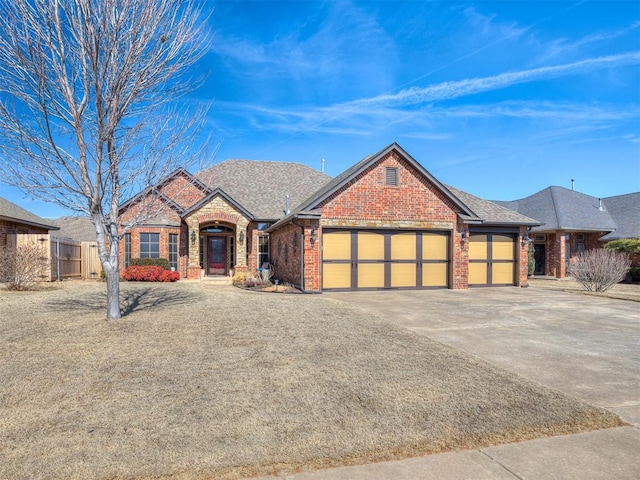 view of front of house featuring a garage, a shingled roof, concrete driveway, fence, and brick siding