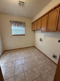 clothes washing area featuring a textured ceiling, washer hookup, visible vents, cabinet space, and electric dryer hookup