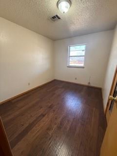 spare room with visible vents, dark wood finished floors, and a textured ceiling