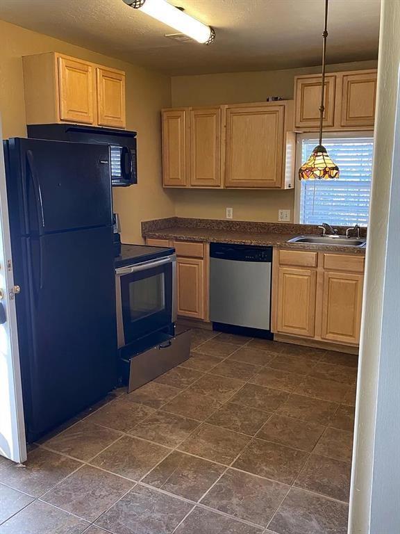 1817 NW 32nd St, Oklahoma City, OK 73118 - kitchen featuring dark countertops, appliances with stainless steel finishes, light brown cabinetry, pendant lighting, and a sink
