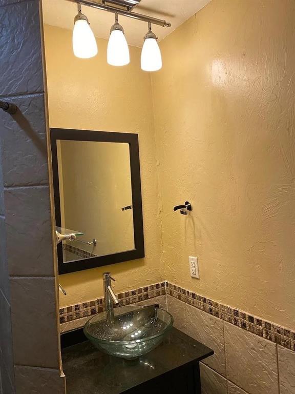 1817 NW 32nd St, Oklahoma City, OK 73118 - bathroom featuring a textured wall, vanity, and tile walls