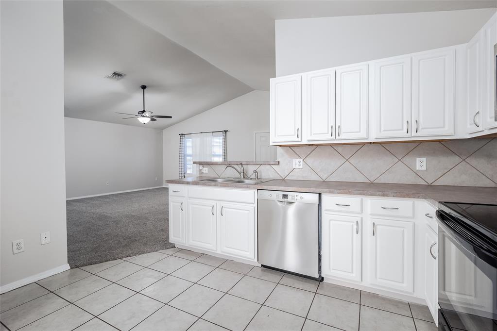 kitchen with visible vents, white cabinetry, open floor plan, vaulted ceiling, and dishwasher