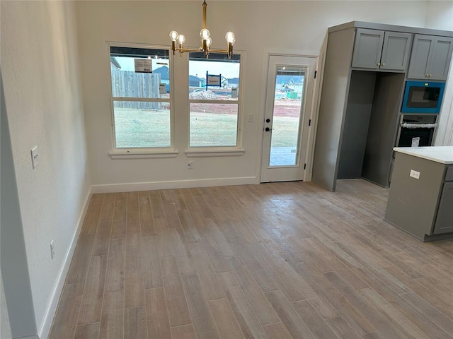 unfurnished dining area featuring light wood finished floors, baseboards, and a chandelier