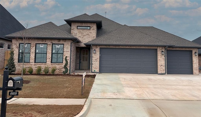 view of front facade with concrete driveway, a shingled roof, an attached garage, and brick siding