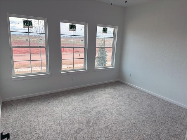 spare room featuring carpet and baseboards