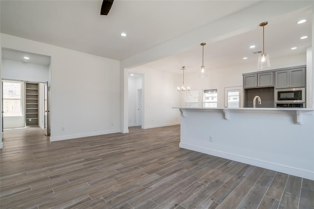 kitchen featuring black microwave, a breakfast bar, wood finished floors, gray cabinetry, and a notable chandelier