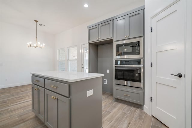 kitchen featuring light wood-style floors, gray cabinets, oven, and built in microwave