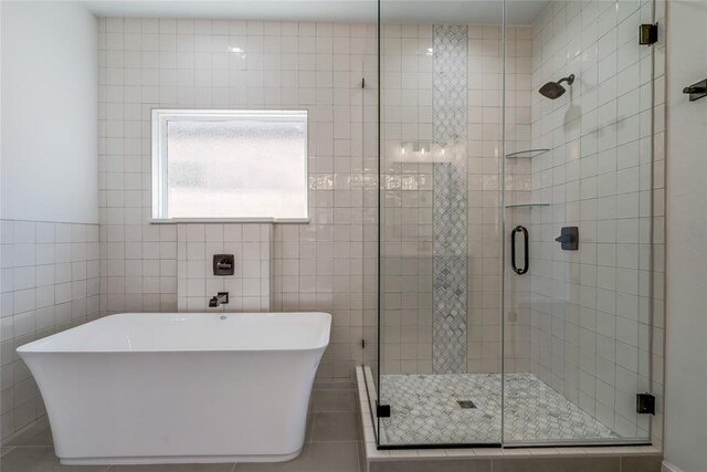 full bathroom featuring tile patterned floors, tile walls, a shower stall, and a freestanding tub