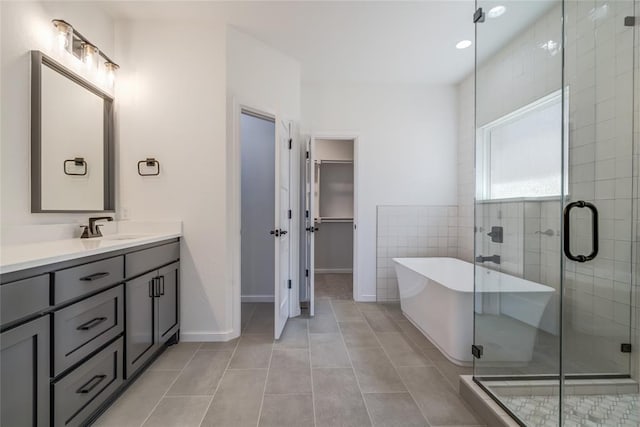 full bath featuring vanity, a stall shower, a soaking tub, a spacious closet, and tile patterned flooring