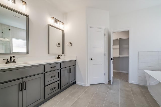 bathroom with a sink, a spacious closet, double vanity, and a freestanding tub