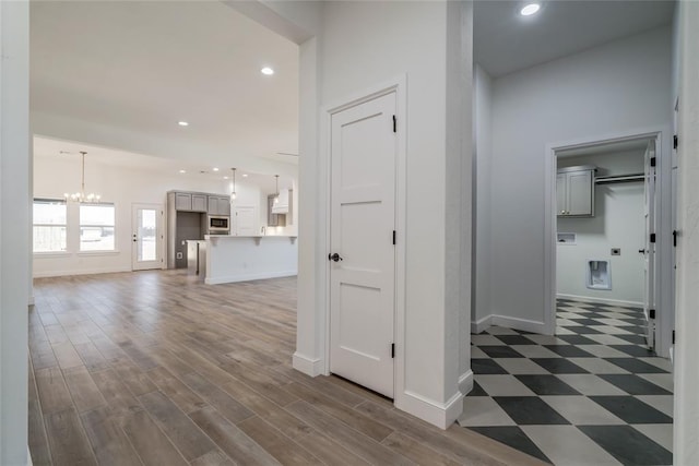 hallway with recessed lighting, a notable chandelier, and baseboards