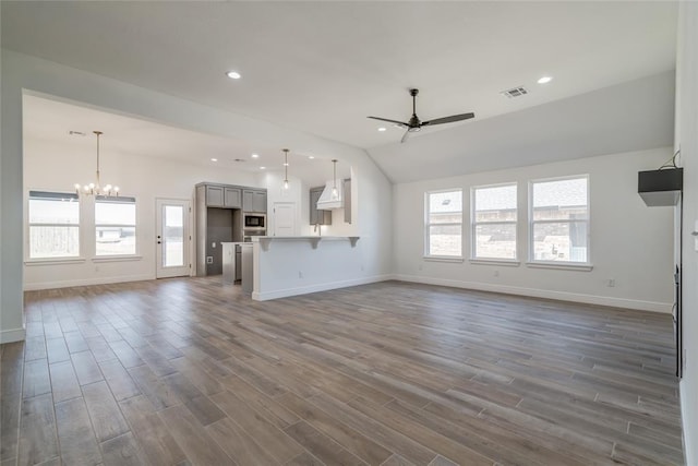 unfurnished living room featuring dark wood finished floors, baseboards, and ceiling fan with notable chandelier