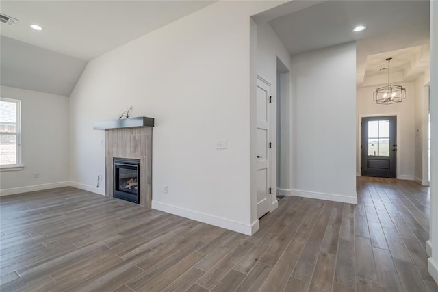 unfurnished living room featuring a wealth of natural light, an inviting chandelier, wood finished floors, and baseboards