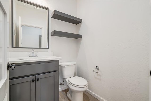 bathroom featuring vanity, baseboards, toilet, and wood finished floors