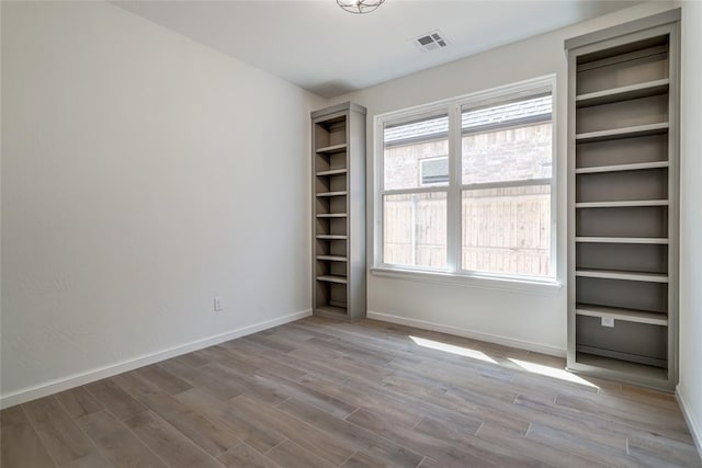 unfurnished bedroom featuring visible vents, baseboards, and wood finished floors