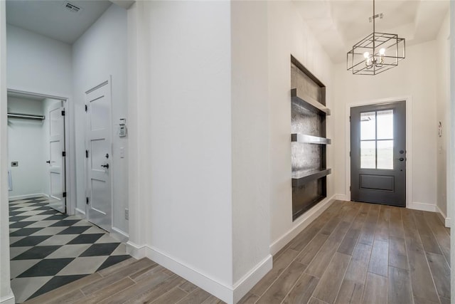entrance foyer featuring visible vents, baseboards, an inviting chandelier, and wood finished floors