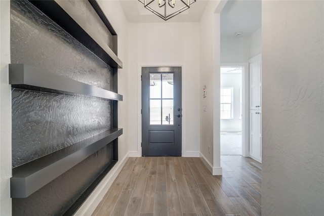 interior space with wood finished floors, an inviting chandelier, and baseboards