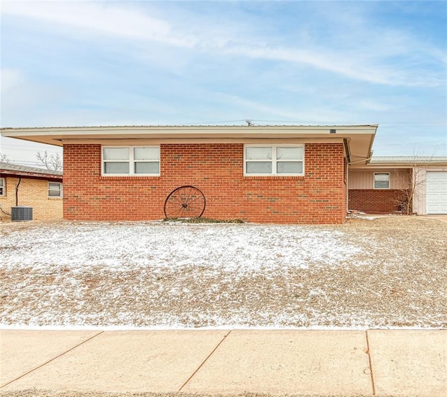 view of front of property with a garage, central AC, brick siding, and driveway