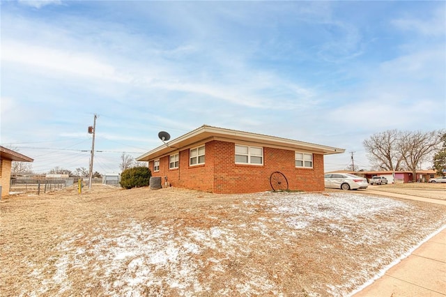 view of property exterior with central AC and brick siding