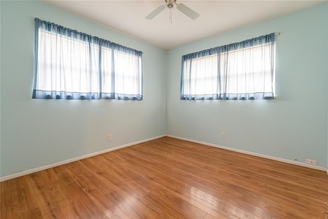 unfurnished room with wood finished floors, a ceiling fan, and baseboards