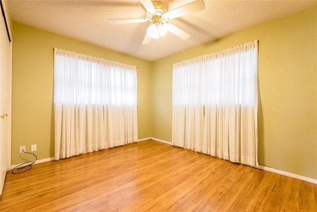 spare room featuring light wood-type flooring, ceiling fan, a textured ceiling, and baseboards