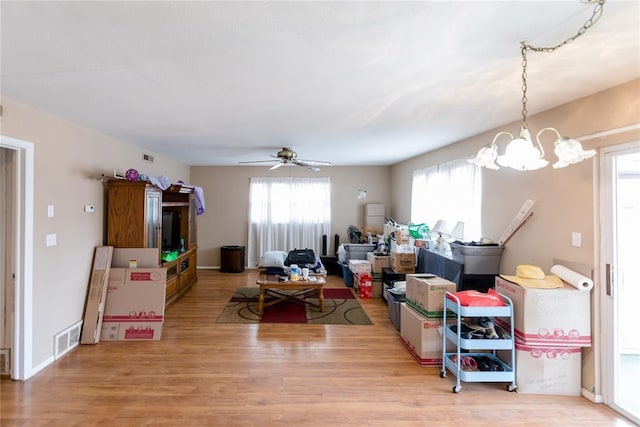 interior space featuring visible vents, wood finished floors, and ceiling fan with notable chandelier