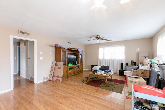 living room featuring light wood-style flooring, visible vents, ceiling fan, and baseboards