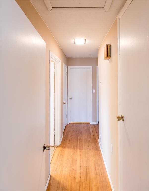 hall with light wood-style floors and baseboards