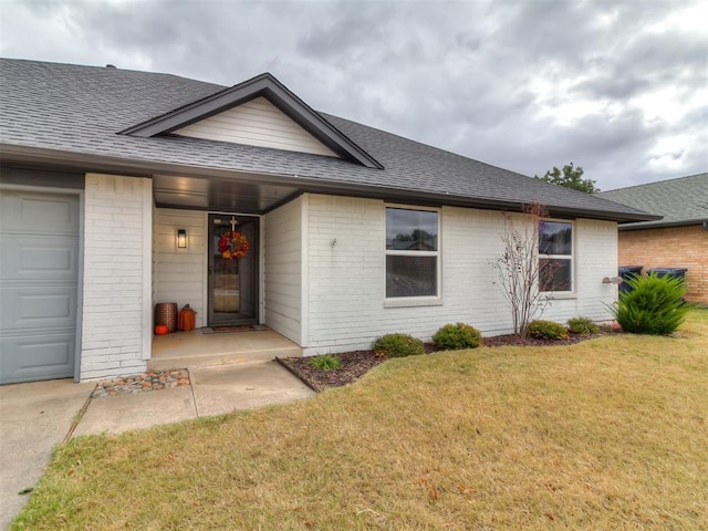 view of front of property featuring brick siding, roof with shingles, an attached garage, and a front lawn